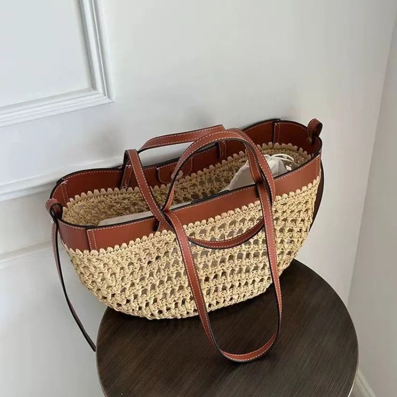 A woven straw tote bag with brown leather trim and handles, resting on a dark wooden stool against a white paneled wall.