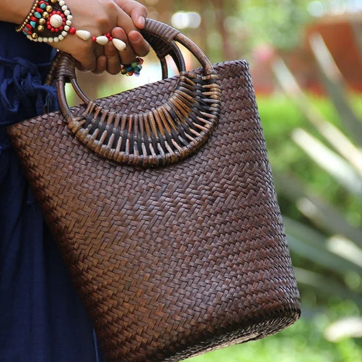 Woven handbag held by a person with a blurred natural background