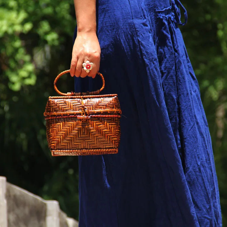 Person holding a woven handbag with a blurred natural background