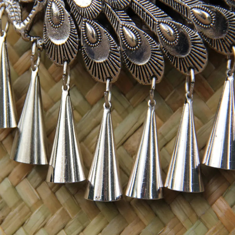 Silver bell-shaped earrings on a woven background