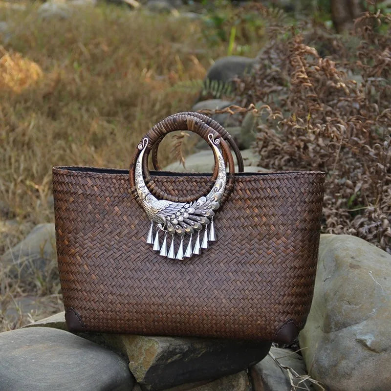 Woven handbag with decorative handle on a stone surface