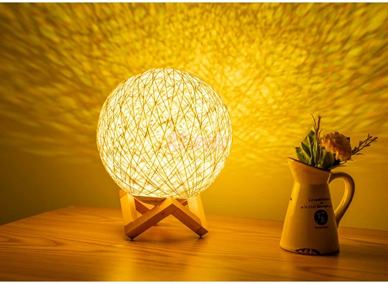 Woven ball lamp on a wooden surface with a yellowish glow