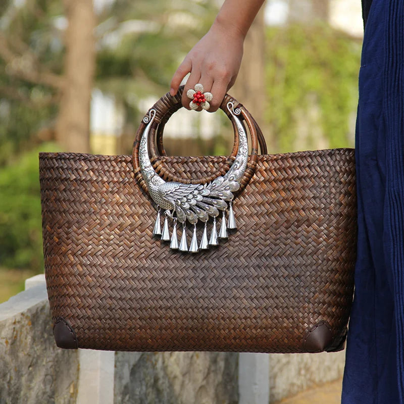 Woven handbag with decorative handle held by a person outdoors