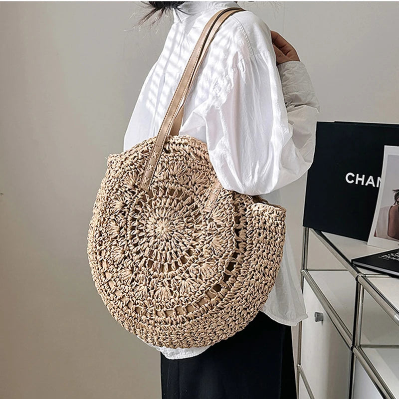 Person holding a woven beige bag in an indoor setting with a blurred background