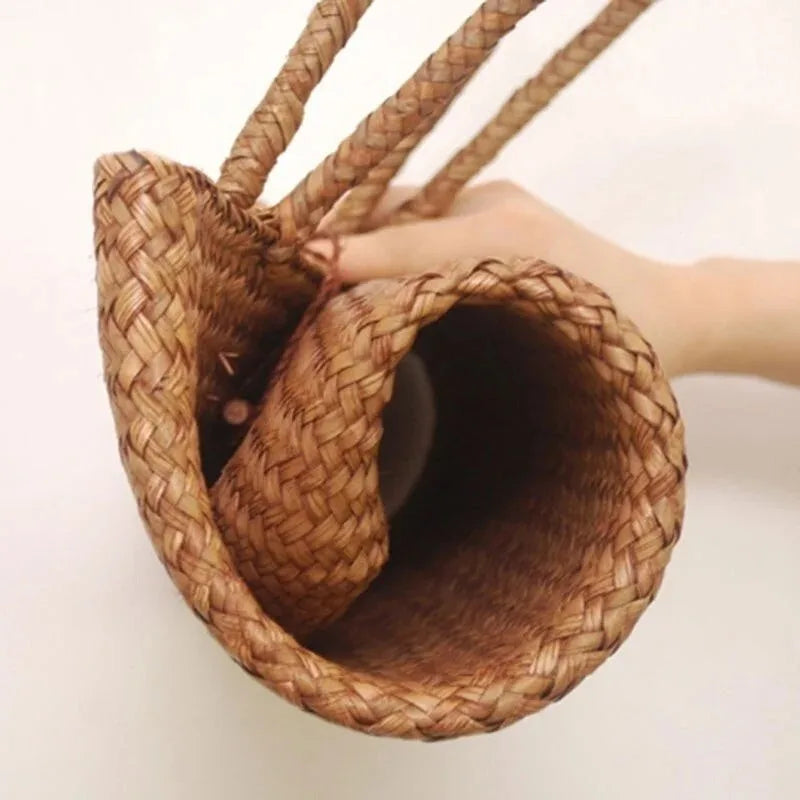 Woven handbag held by a hand on a light background