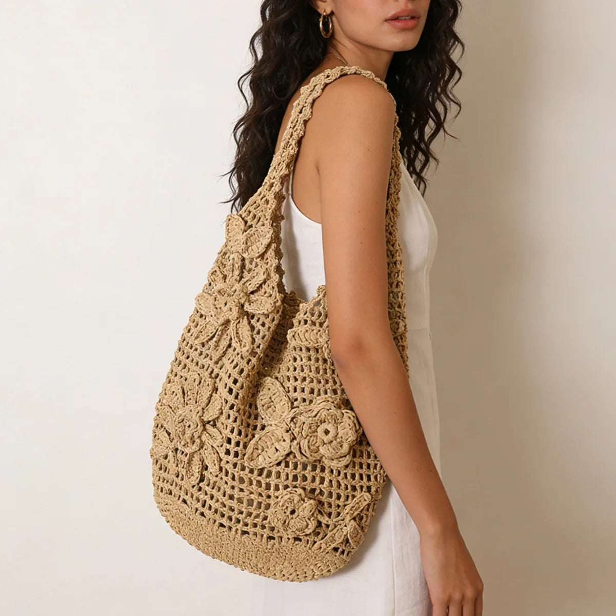 Woman carrying a beige crochet bag against a neutral background