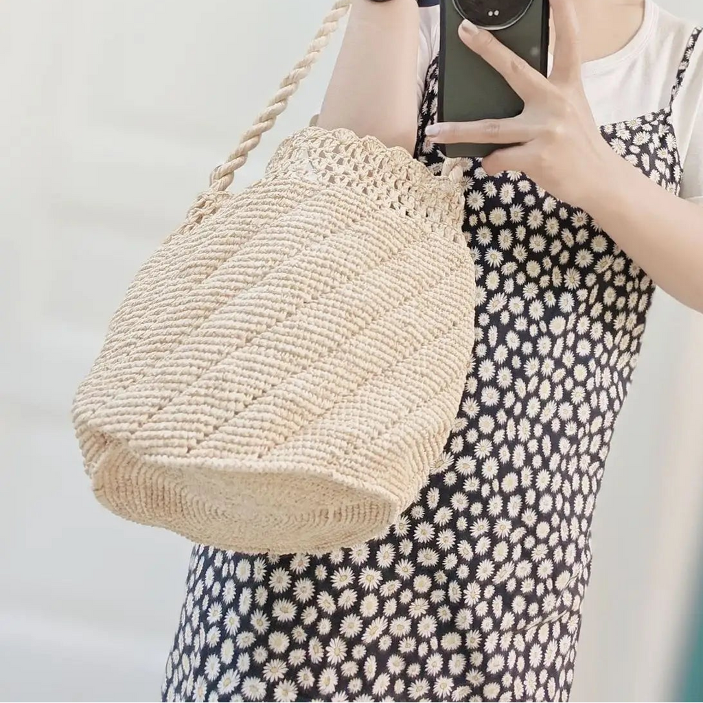 Person taking a mirror selfie wearing a straw hat, white top, and polka dot dress, holding a woven bag.