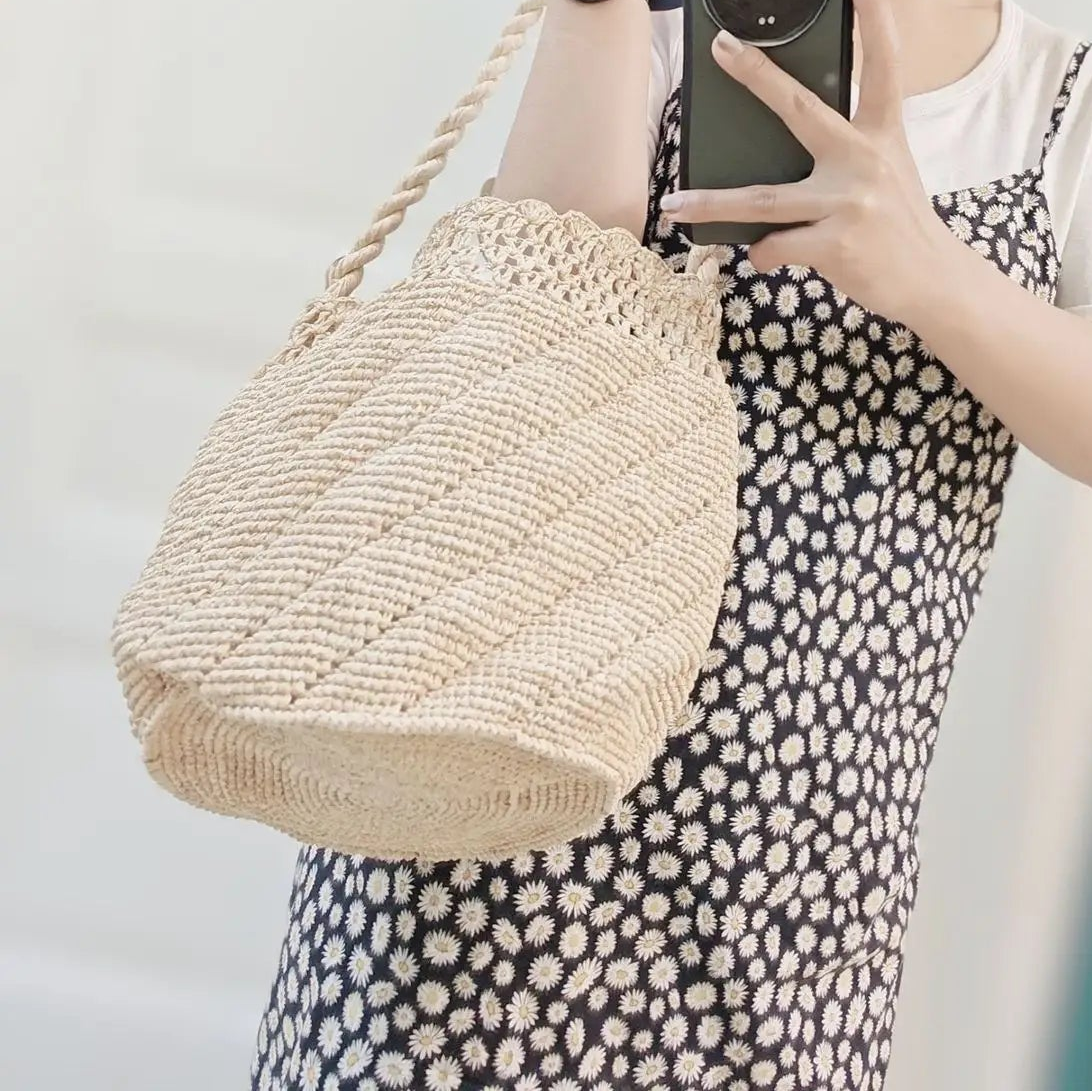 Person taking a mirror selfie wearing a straw hat, white top, and polka dot dress, holding a woven bag.