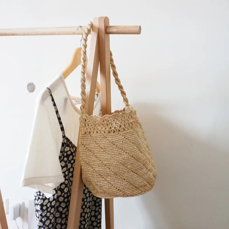 Woven bag hanging on a wooden rack with a white wall background