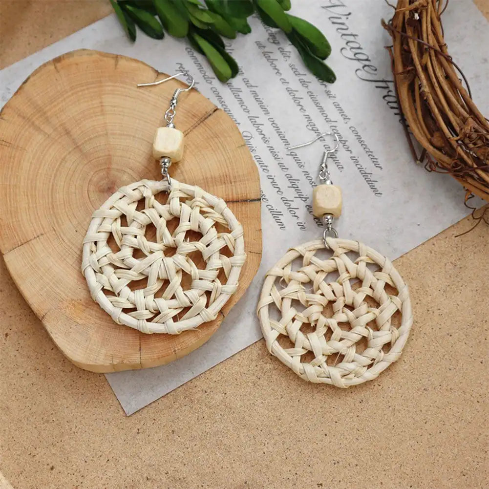 Pair of woven earrings on a wooden surface with a natural background