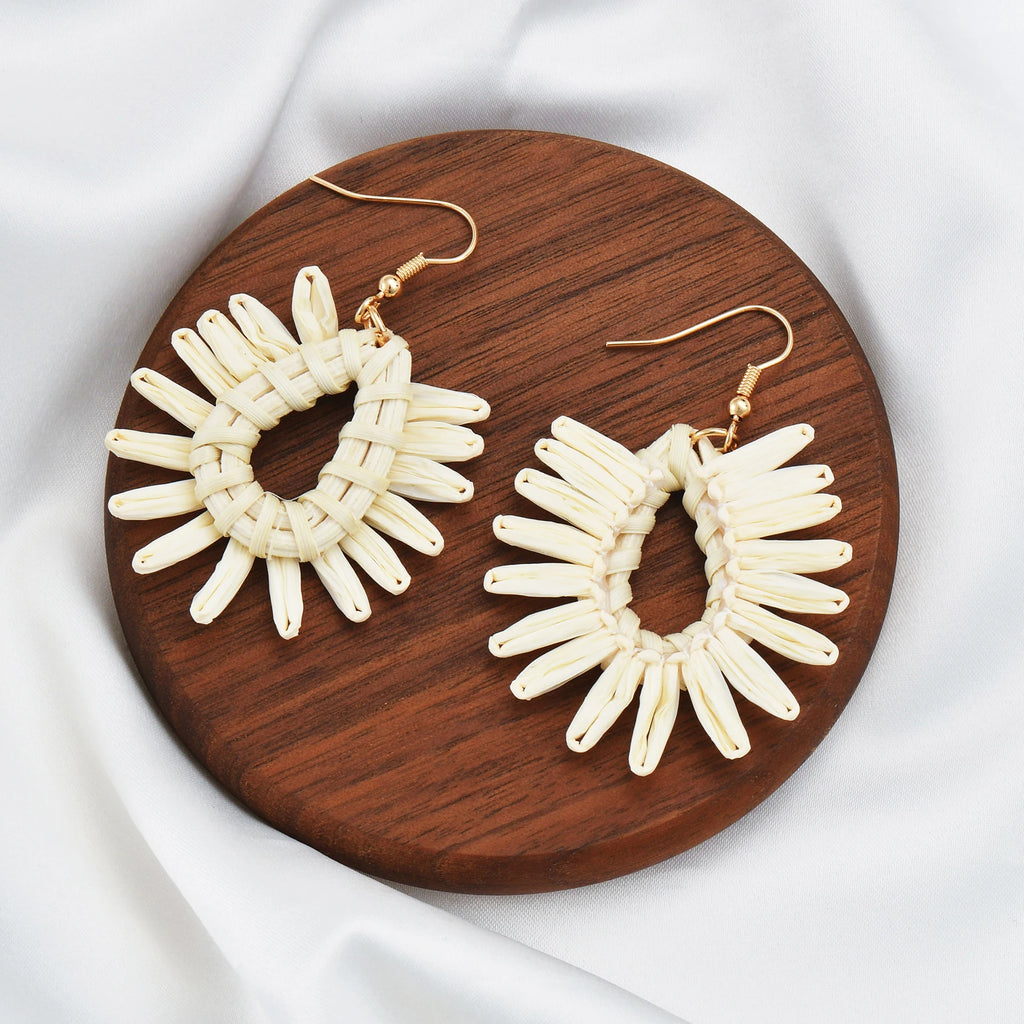 Pair of white hoop earrings on a wooden board with a white background
