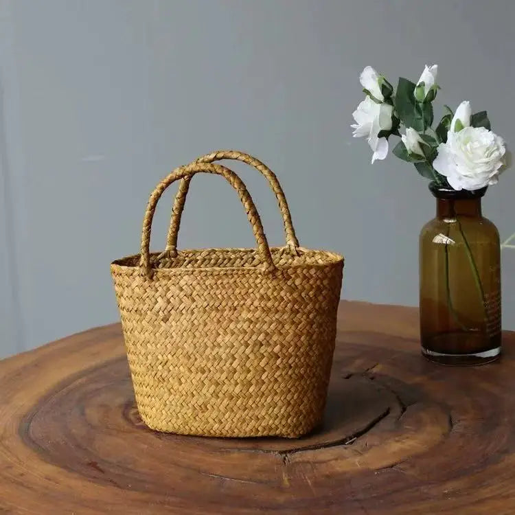 Woven basket on a wooden surface with a vase of flowers in the background