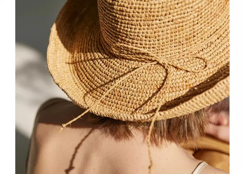 Close-up of a straw hat with a decorative bow on a neutral background