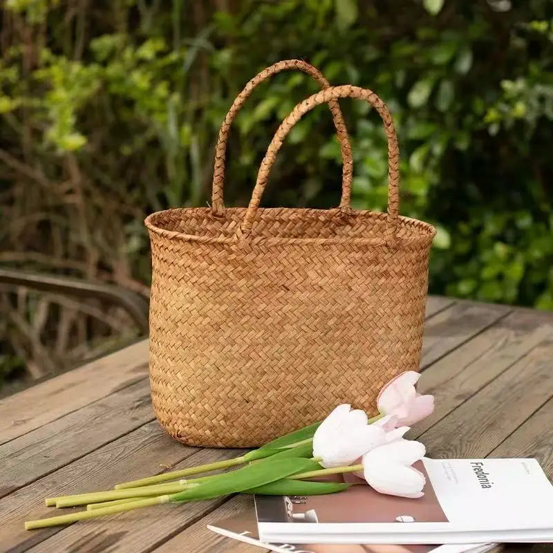 Woven basket on a wooden table with tulips and a magazine, outdoor setting