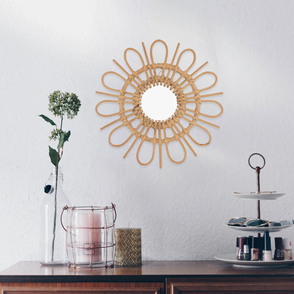 Decorative wall mirror with rattan design on a white wall above a wooden surface with decorative items.