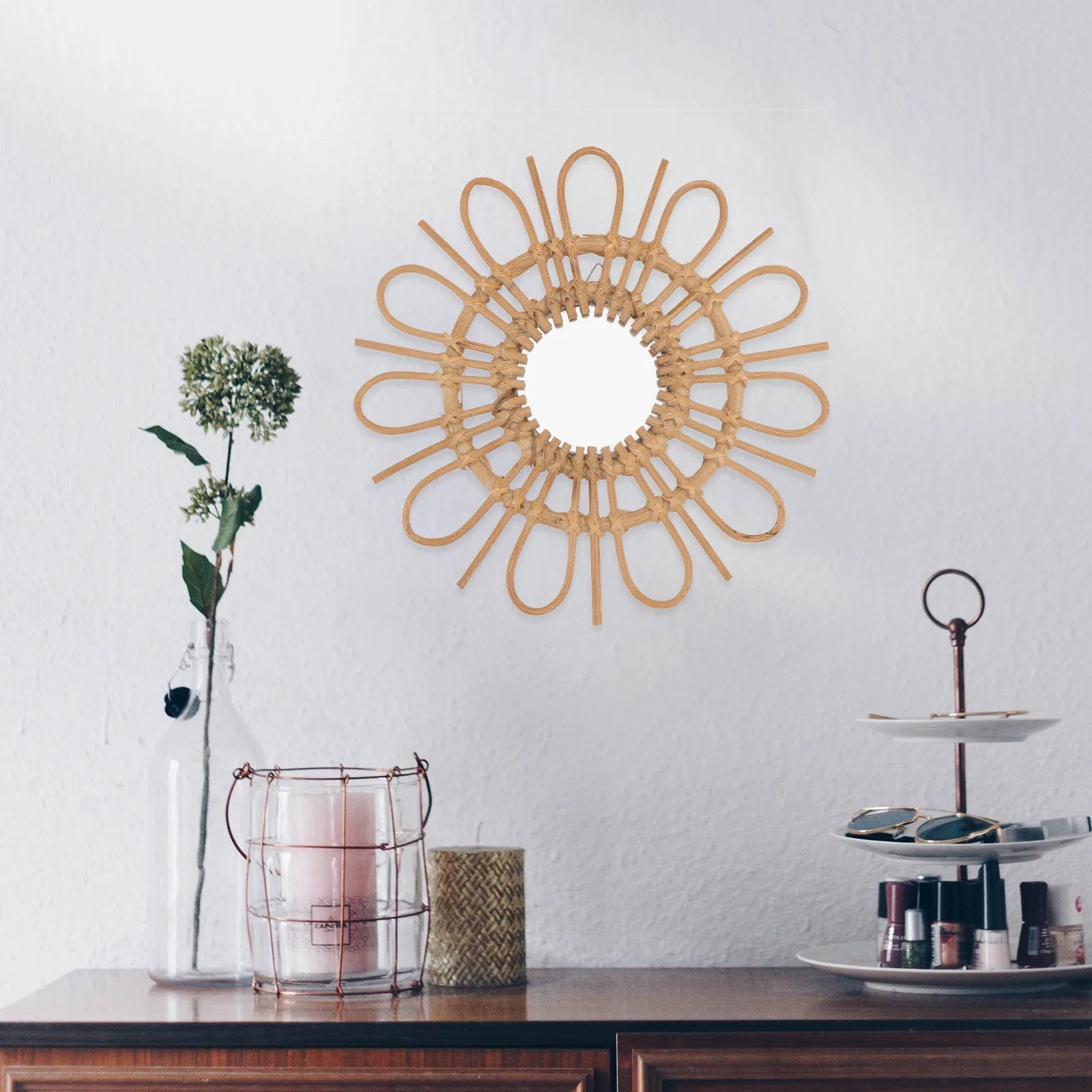 Decorative wall mirror with rattan design on a white wall above a wooden surface with decorative items.