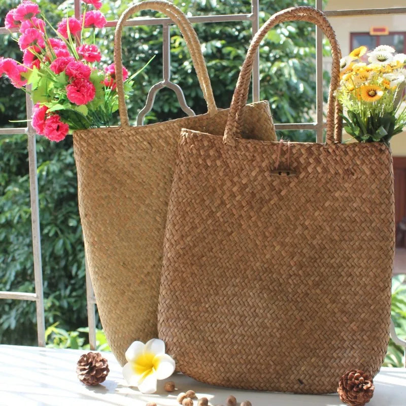 Two woven bags with flowers and decorative elements on a table outdoors.