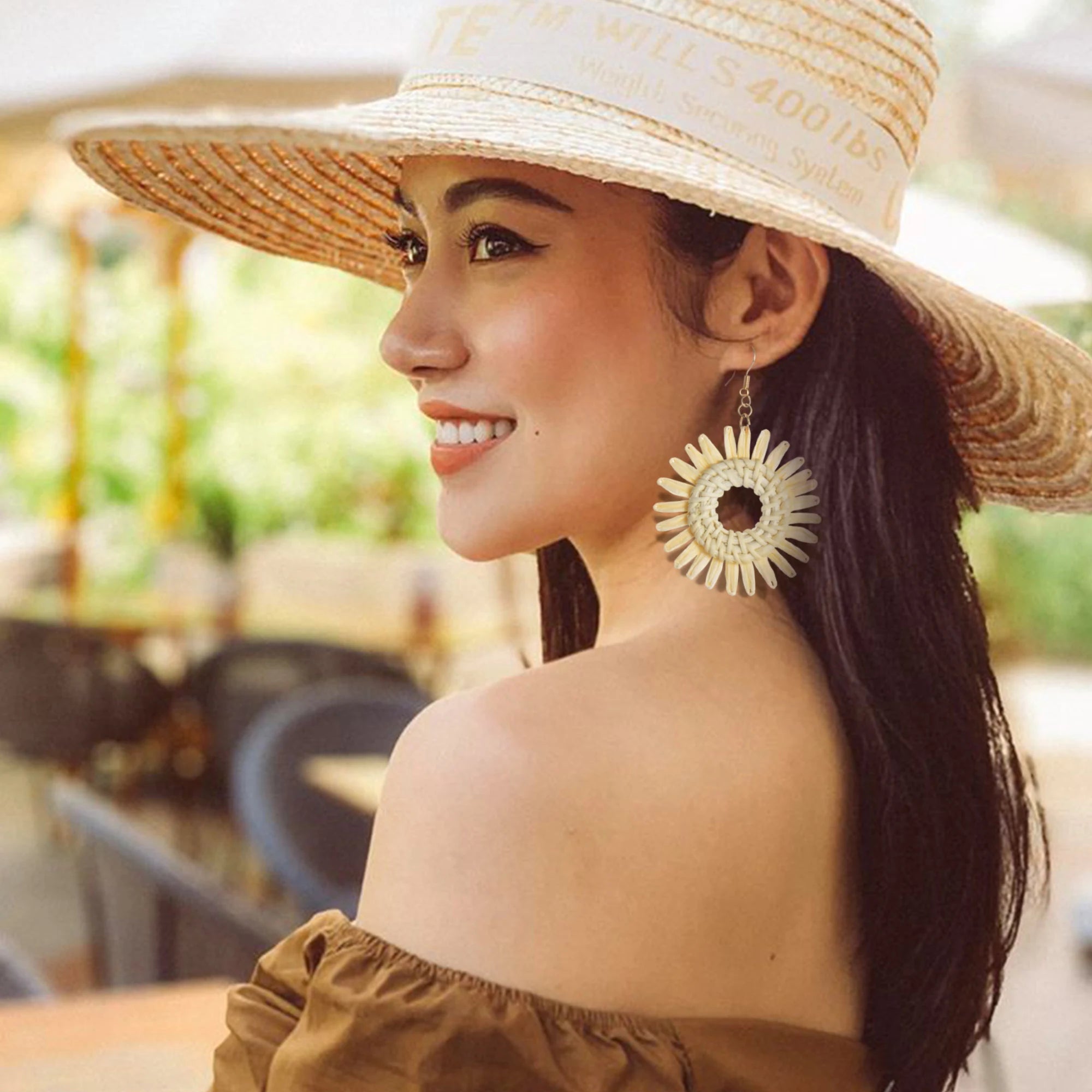 Woman wearing a straw hat and large earrings outdoors