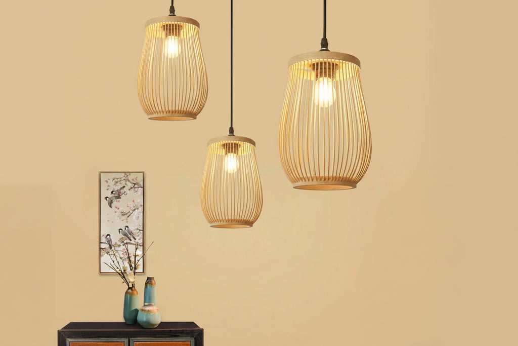 Three gold wire pendant lights hanging against a beige wall with a decorative painting and vases.