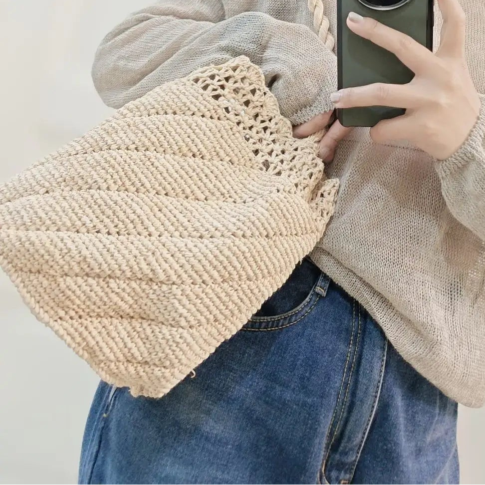 Person wearing a straw hat and holding a woven bag, taking a mirror selfie.