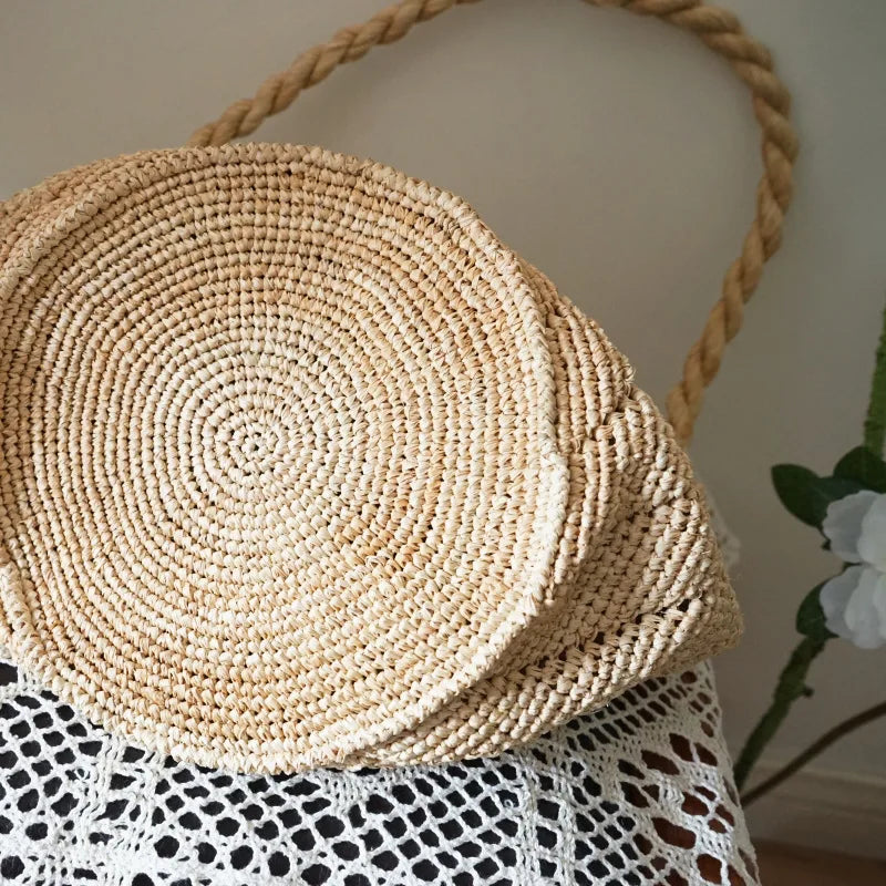Round woven bag with a rope handle on a textured surface