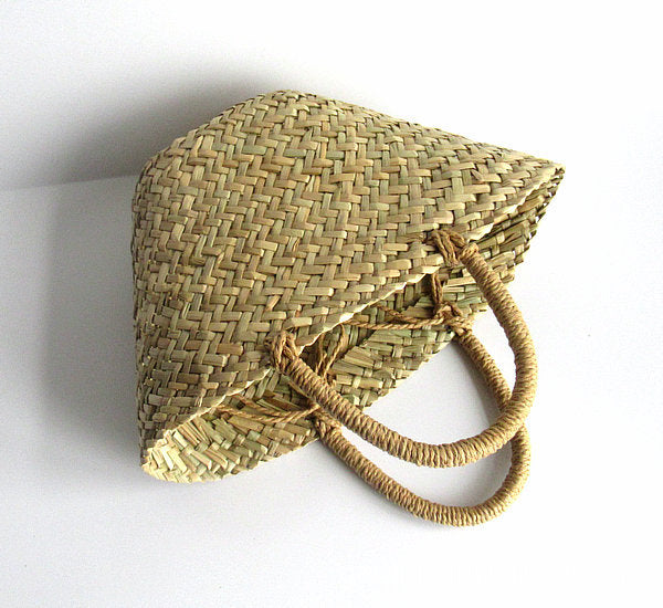 Woven straw hat with a handle on a white background