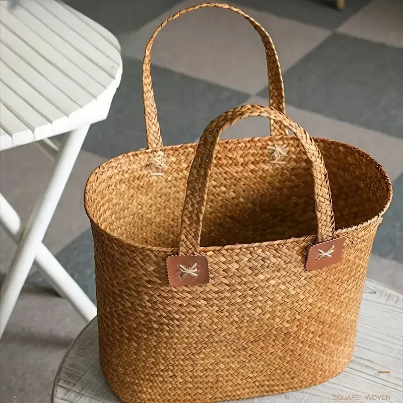 Woven basket with handles on a surface, with a chair in the background