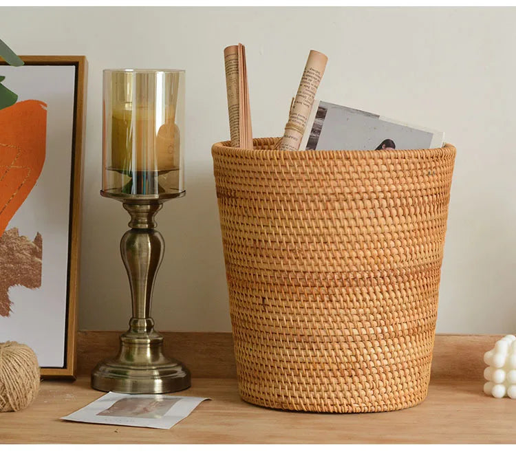 Woven basket on a wooden surface with a candle and books, against a neutral wall.