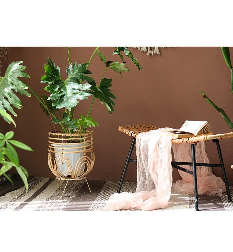 Indoor setting with a plant in a woven basket, a chair with a pink cloth, and a book on a brown wall.