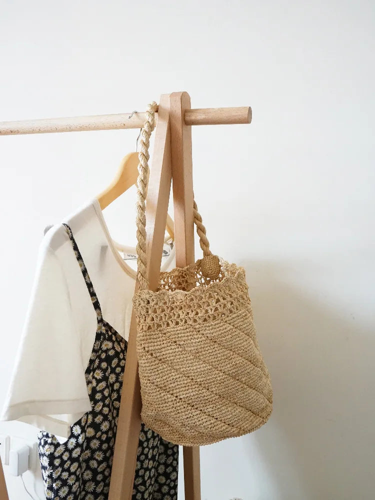 Woven bag hanging on a wooden hanger against a white wall