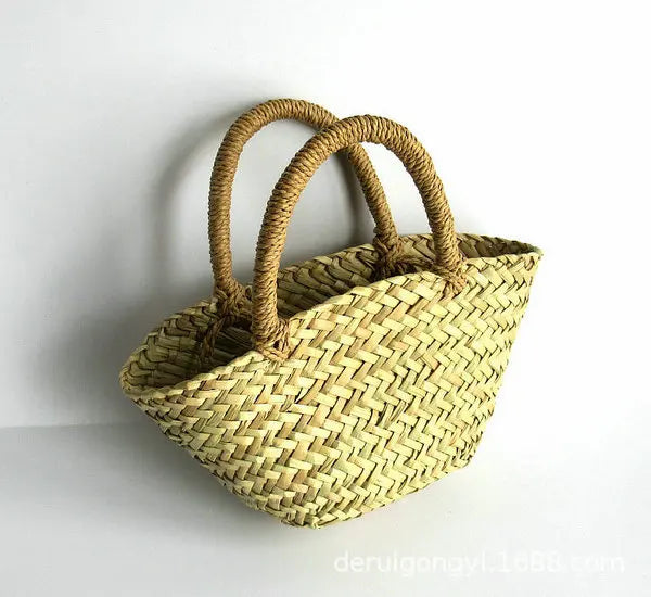 A natural straw woven tote bag with two thick, rolled top handles, shown against a plain white background.