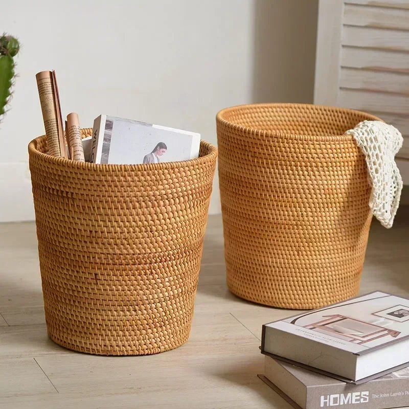 Two woven baskets on a wooden floor with books and a plant.