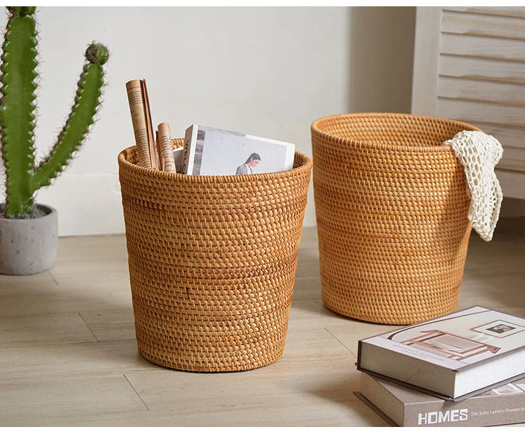 Two woven baskets on a wooden floor with books and a plant.