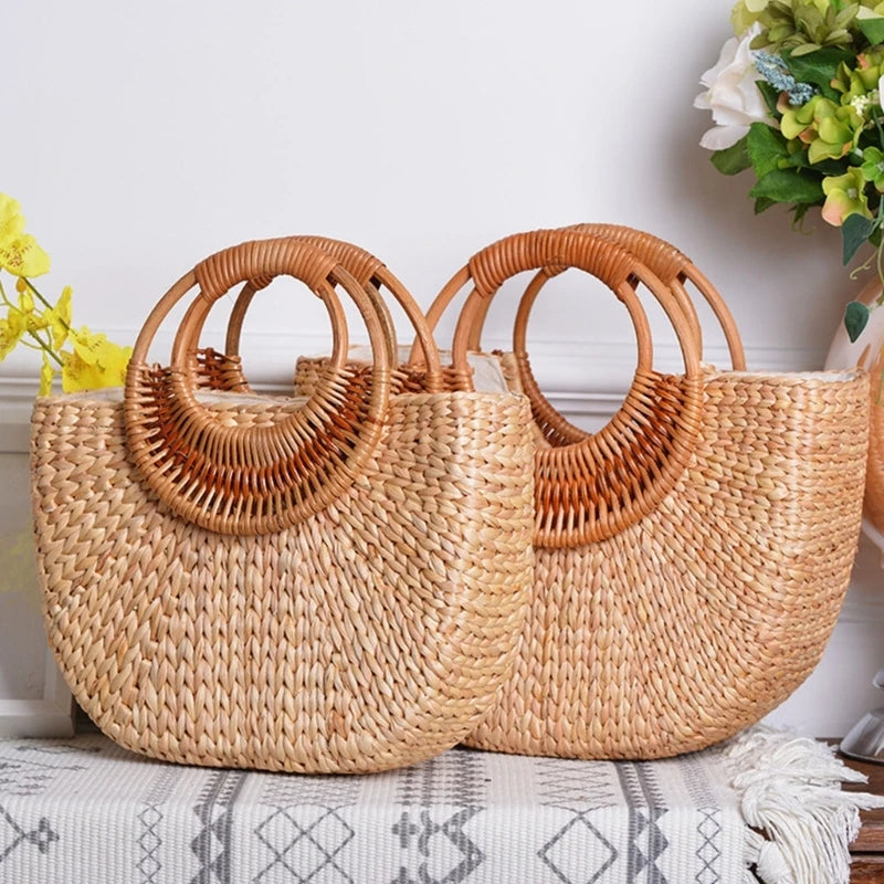 Two woven handbags with circular handles on a surface with flowers in the background.