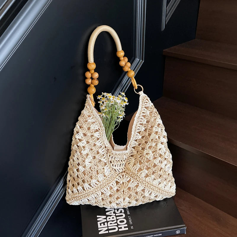Crocheted handbag with wooden handle and beads on a book against a dark background