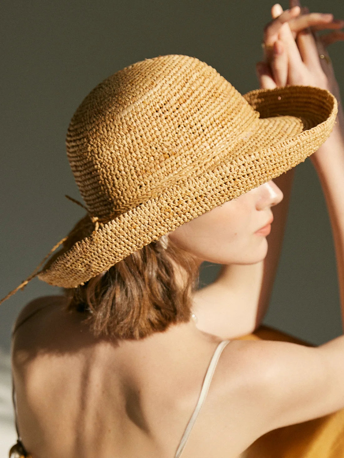Woman wearing a straw hat against a neutral background