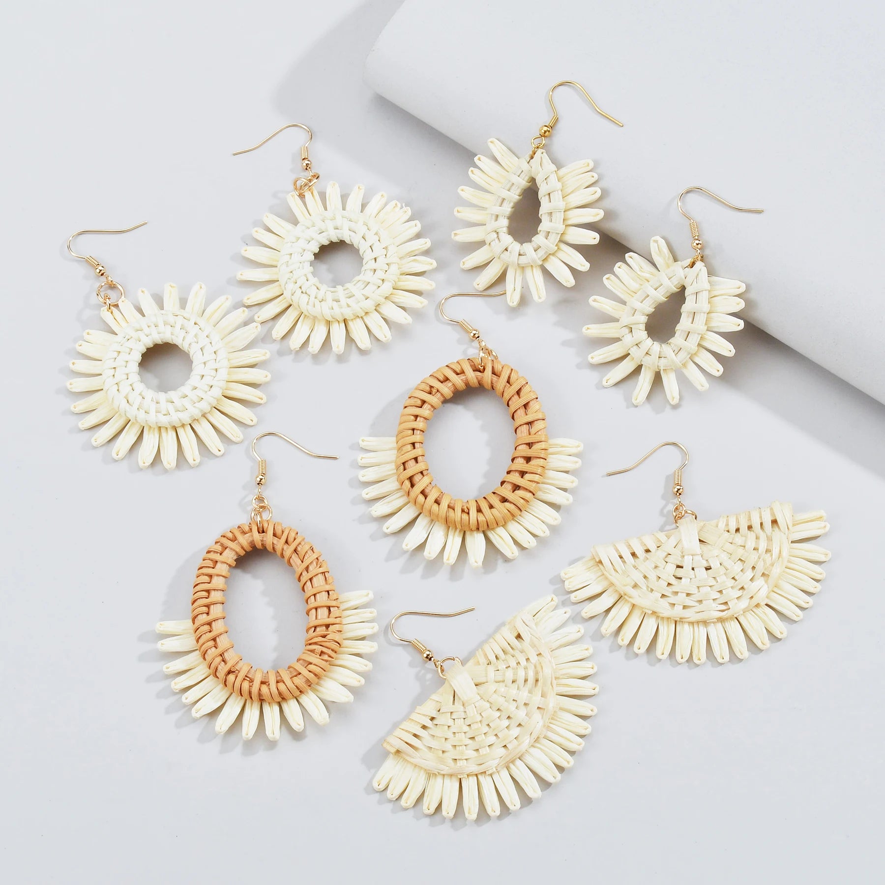 Set of six pairs of raffia earrings in various designs on a light gray background