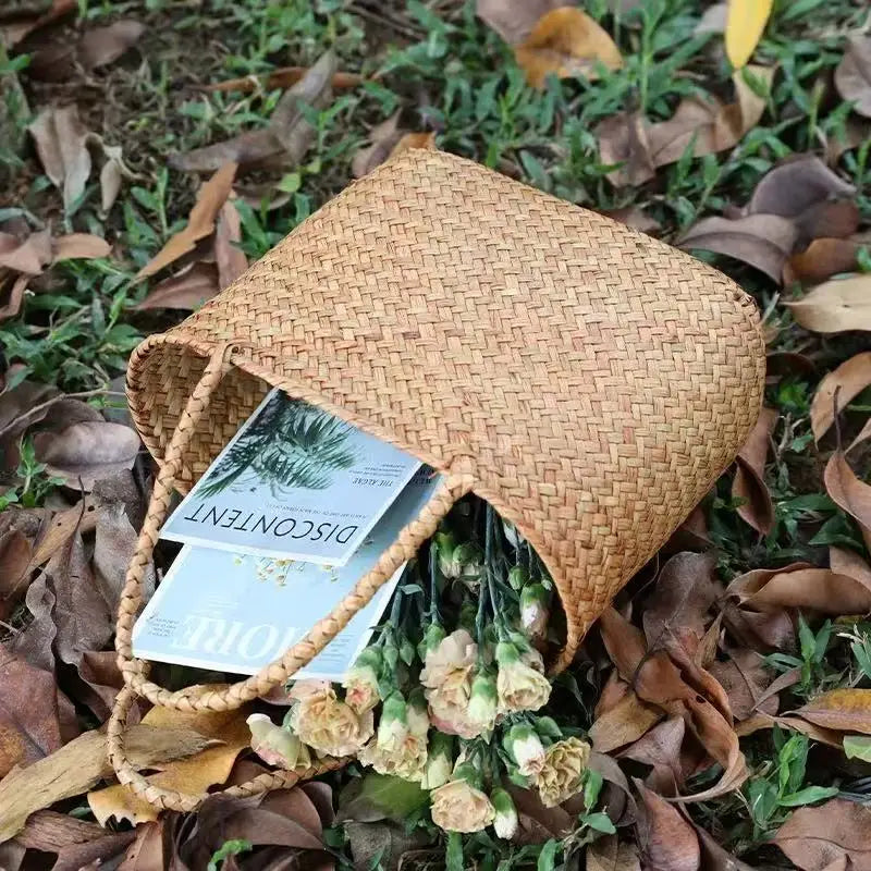 Woven basket with flowers and a book on a grassy background