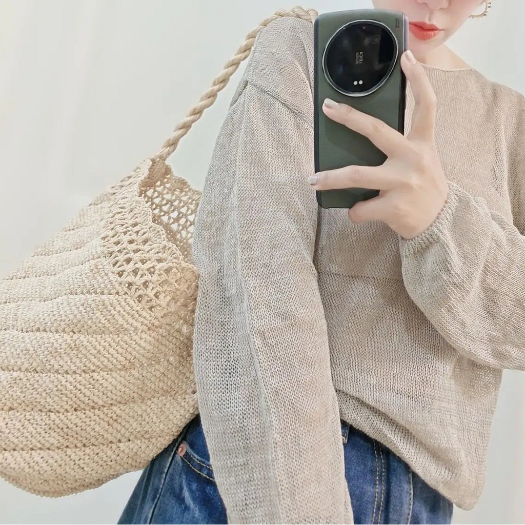 Person wearing a straw hat and beige cardigan taking a mirror selfie.