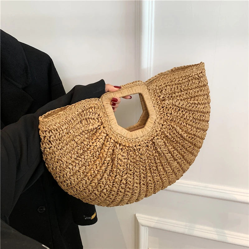 Person holding a woven handbag against a neutral background