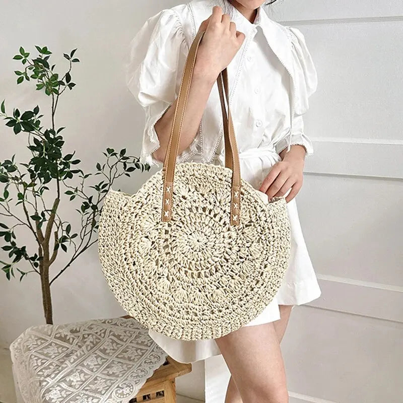 Person holding a woven beige bag with a plant and stool in the background