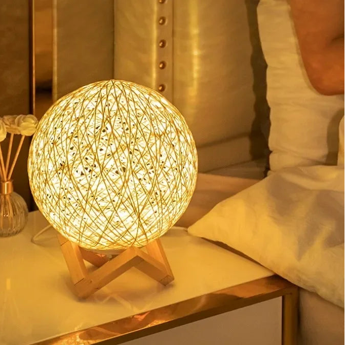 Round woven lamp on a nightstand with warm glow, Kieron logo visible.