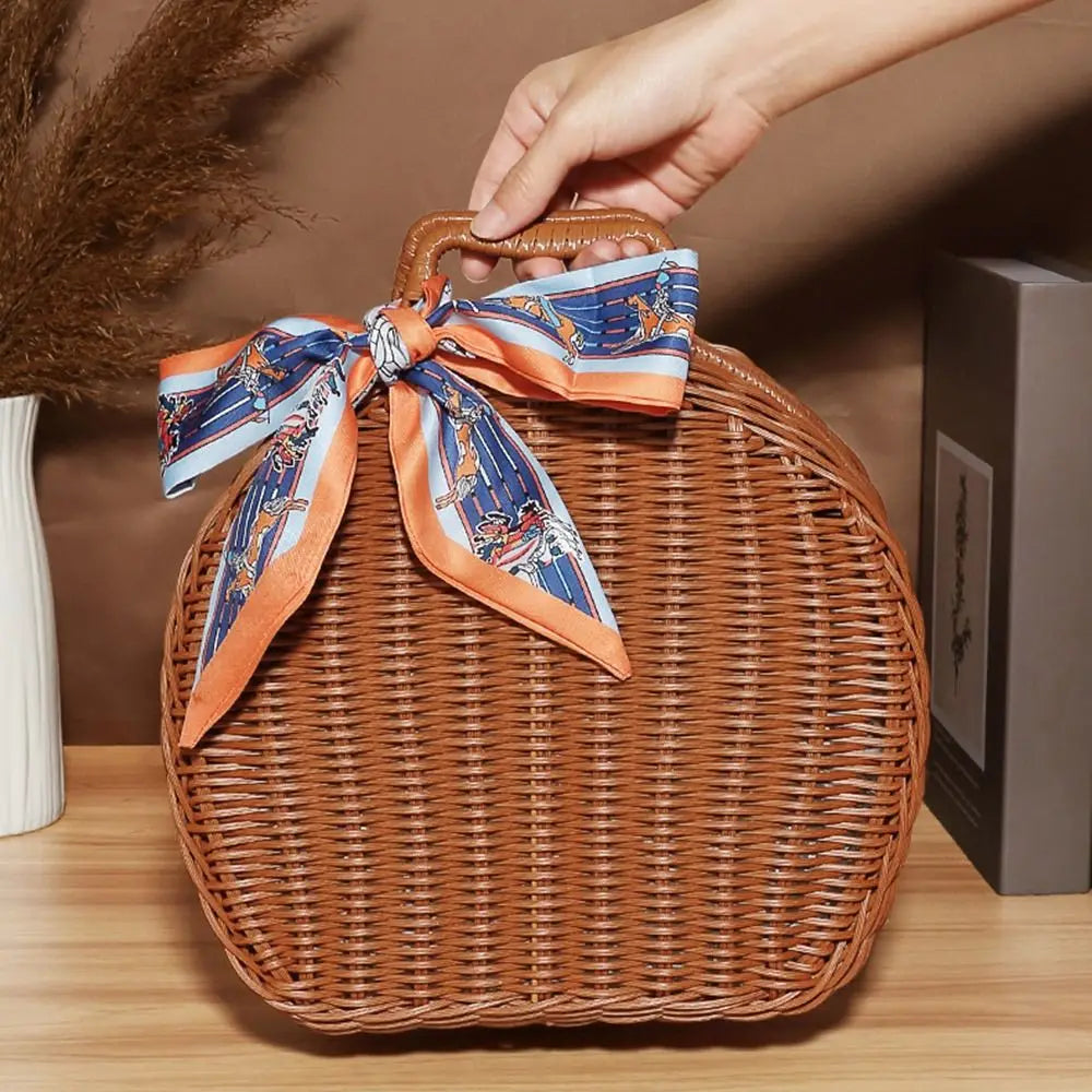 Wicker handbag with decorative ribbon held by a hand on a wooden surface.