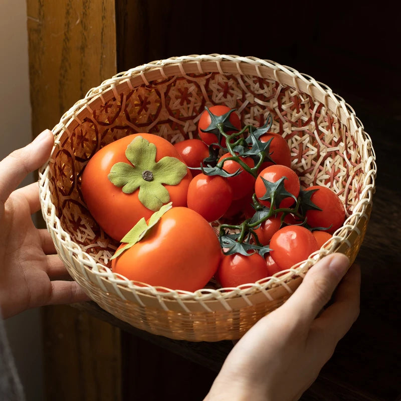 Wicker basket with persimmons and cherry tomatoes held by a hand.