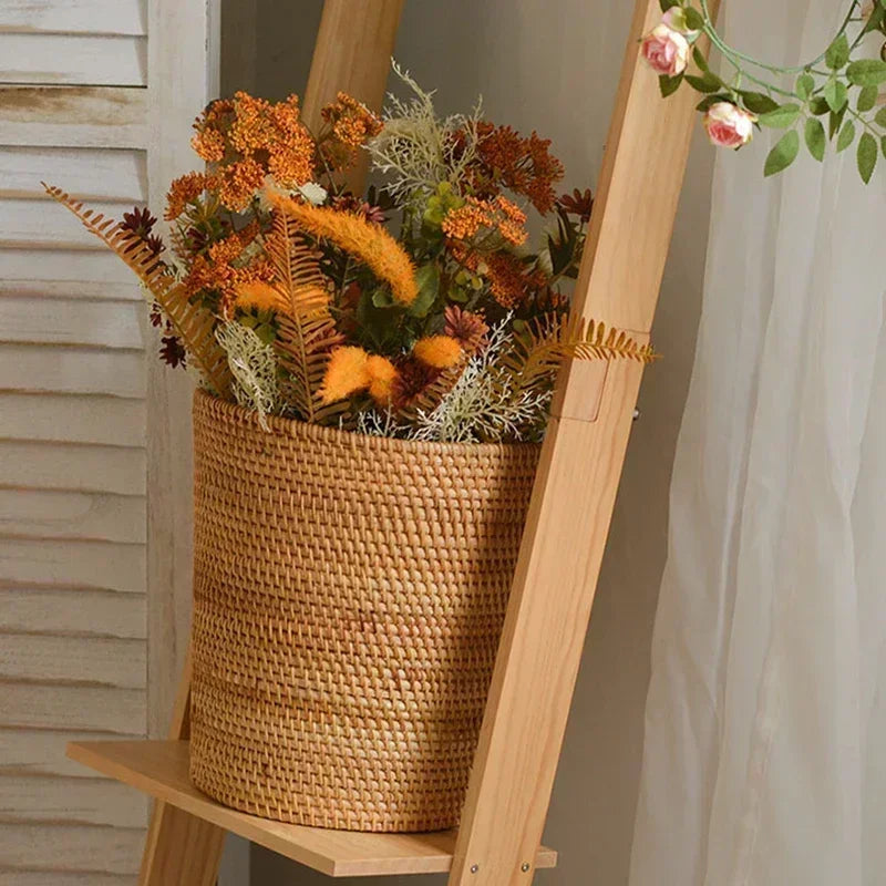 Woven basket with autumn-themed floral arrangement on a wooden stand.
